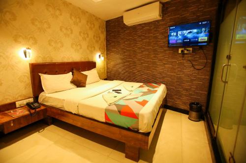 een slaapkamer met een bed en een tv aan een bakstenen muur bij Hotel Garden Creek Residency - Near Mumbai International Airport Andheri East in Mumbai