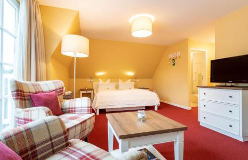 a hotel room with a bed and two chairs at Hotel Landhaus Ellerbrock in Sankt Peter-Ording