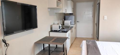 a small kitchen with a television and a table in a room at Sunvida Tower Stays Across SM City Cebu in Cebu City