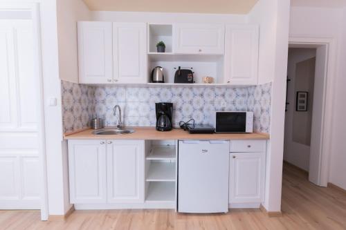a kitchen with white cabinets and a sink at Villa Lilith Smart in Fertőrákos