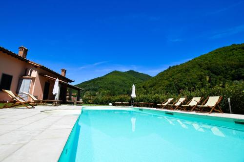 a swimming pool with two chairs and a house at Gattaia Apartments with swimming pool in Gattaia