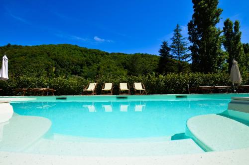 a swimming pool with chairs and umbrellas at Gattaia Apartments with swimming pool in Gattaia