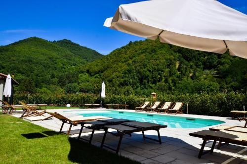 a swimming pool with chairs and an umbrella at Gattaia Apartments with swimming pool in Gattaia