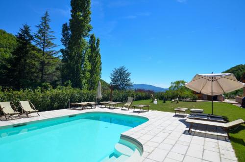 a swimming pool with chairs and an umbrella at Gattaia Apartments with swimming pool in Gattaia