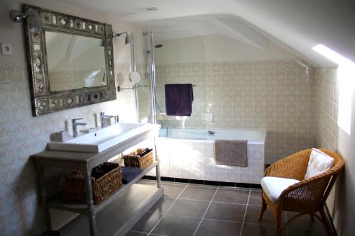 La salle de bains est pourvue d'une baignoire, d'un lavabo et d'un miroir. dans l'établissement Le Domaine Du Cormier, à Orvault