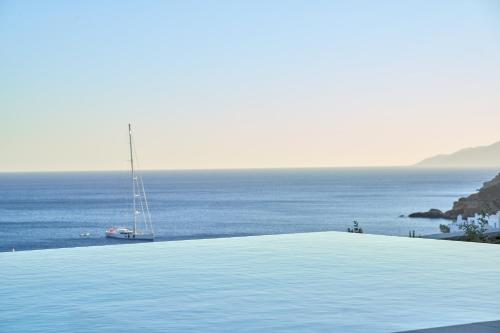 a swimming pool with a sail boat in the ocean at Ios Grand Pool Suites in Mylopotas