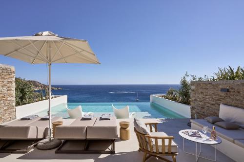 a patio with a table and an umbrella and a pool at Ios Grand Pool Suites in Mylopotas