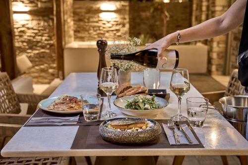 a person pouring wine into a table with food at Ios Grand Pool Suites in Mylopotas