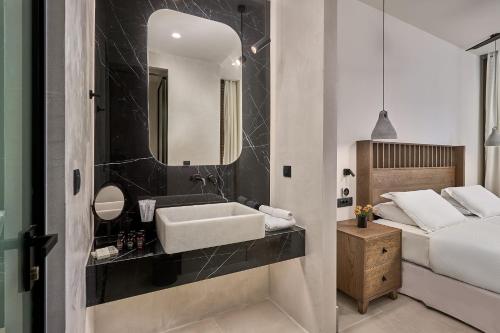 a bathroom with a sink and a bed and a mirror at Ios Grand Pool Suites in Mylopotas