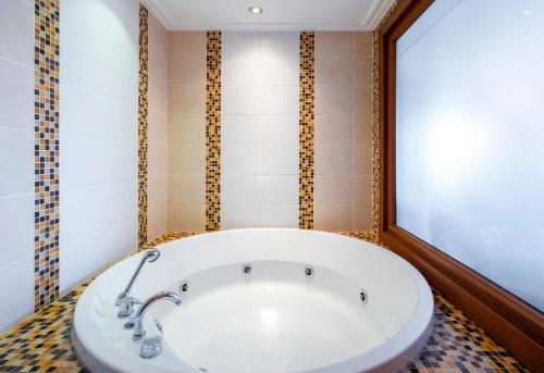 a bath tub in a bathroom with a tiled floor at Bera Alanya Hotel - Halal All Inclusive in Konaklı