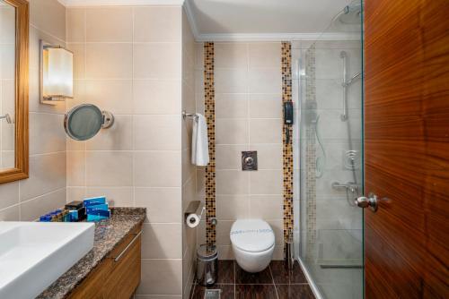 a bathroom with a toilet and a glass shower at Bera Alanya Hotel - Halal All Inclusive in Konaklı