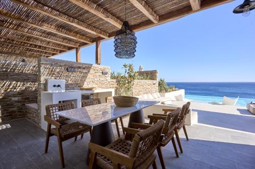 a dining table and chairs on a patio with the ocean at Ios Grand Pool Suites in Mylopotas