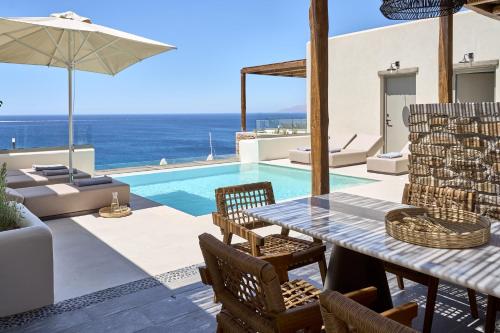 a patio with a table and chairs and a pool at Ios Grand Pool Suites in Mylopotas