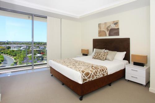 um quarto com uma cama e uma grande janela em Signature Waterfront Apartments em Gold Coast