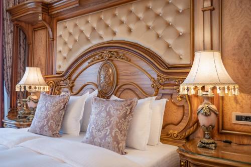 a bedroom with a bed with a wooden headboard and two lamps at Prezident Palace Belgrade - Adults Only in Belgrade