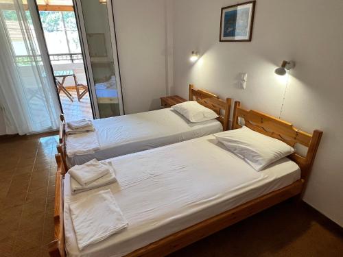 two twin beds in a room with a balcony at ERIDA Accommodation in Lákka