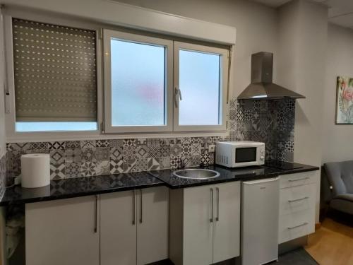 a kitchen with a counter with a microwave and two windows at Apartamento en Bilbao con Wifi al lado del metro in Bilbao