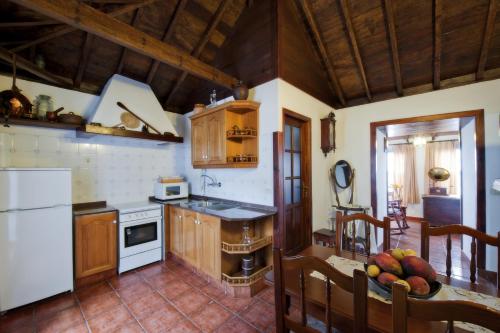 una cocina con electrodomésticos blancos y una mesa con fruta. en Casa Rural Tio Pedro, en Mazo