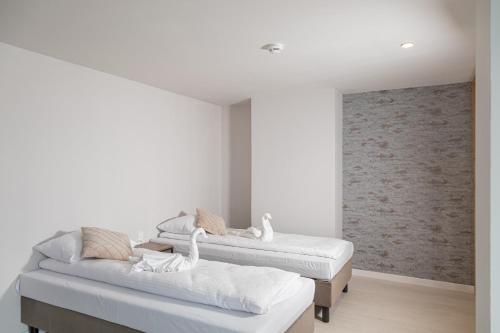 two beds in a room with white walls at Sudecki Resort & SPA in Karpacz