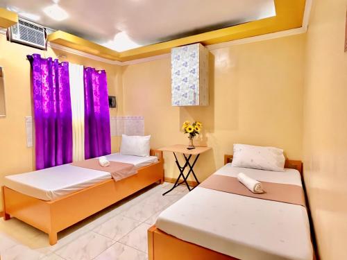 una habitación con 2 camas y una mesa con flores en Wency Amor Hotel, en Sablayan