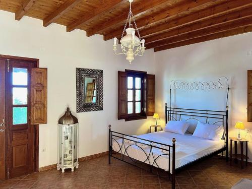 een slaapkamer met een bed en een kroonluchter bij Litois Houses Patmos in Sapsila