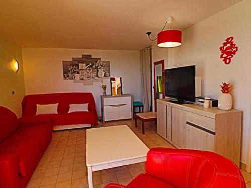 un salon avec un canapé rouge et une télévision dans l'établissement Studio Cabine à Sète: Terrasse, Jardinet, Piscine et Parking Privé à Proximité de la Mer - FR-1-472A-141, à Sète