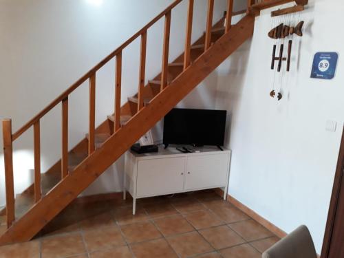 uma sala de estar com uma televisão num armário debaixo de uma escada em CASA SÃO SEBASTIÃO Casas Bem Haja em São Miguel de Acha