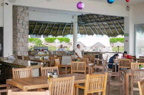 a restaurant with wooden tables and chairs and people in the background at Cancun Plaza Condo Ocean front in Cancún