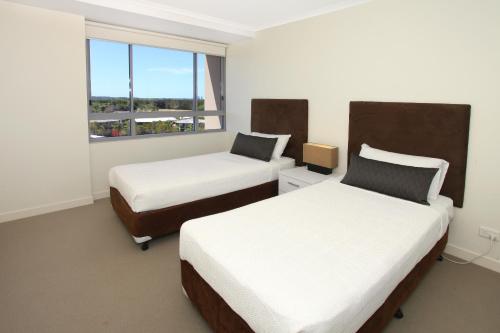 a hotel room with two beds and a window at Signature Waterfront Apartments in Gold Coast