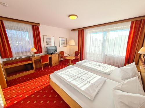 a hotel room with two beds and a television at Thermenhotel Tannenhof - Ihr Wohlfühl-Hotel in Bad Füssing