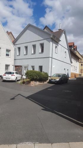 deux voitures garées devant un bâtiment blanc dans l'établissement Ferienwohnung Höhn, à Kitzingen