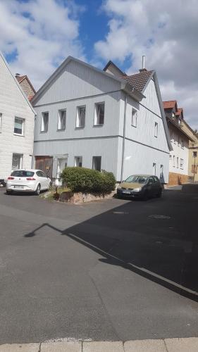 twee auto's geparkeerd voor een wit gebouw bij Ferienwohnung Höhn in Kitzingen