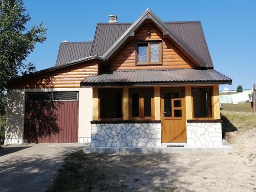 a house with a garage and a red door at Bungalows and rooms Ivan in Žabljak