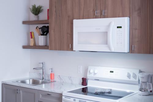 a white kitchen with a sink and a microwave at Le Central in Rouyn