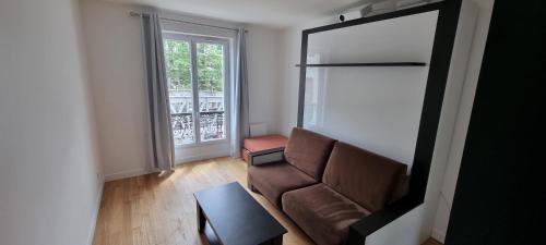a living room with a couch and a window at PARIS AURIOL in Paris