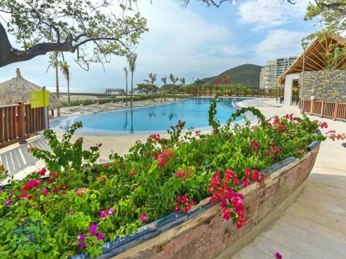 a swimming pool with flowers in front of a resort at Club de Playa Samaria - T1 APTO 1705, Santamarta in Santa Marta