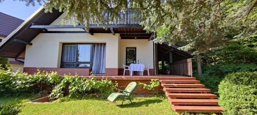 a house with a deck and a chair in the yard at Domek na Porąbkach z kominkiem in Międzybrodzie Żywieckie