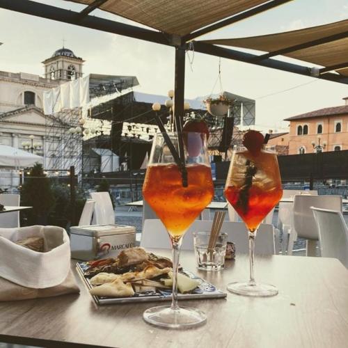 two drinks on a table with a plate of food at Piazza del Mercato in LʼAquila