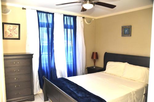 - une chambre avec un lit doté de rideaux bleus et d'un ventilateur de plafond dans l'établissement The president room 5 minutes to Devon House 6 strathairn Avenue Kingston, à Kingston