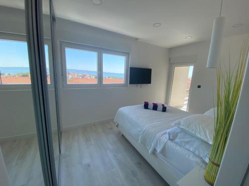 a white bedroom with a bed and two windows at Villa Tri Brata in Podstrana