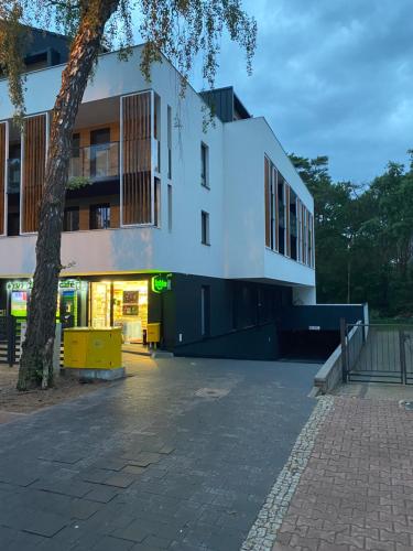 un edificio bianco con un albero di fronte di Apartamenty na wydmach &Spa a Pobierowo