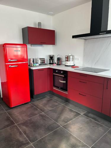 Il comprend une cuisine équipée de placards rouges et d'un réfrigérateur rouge. dans l'établissement Appartement dans maison avec cour et parc, à Fresnes-en-Woëvre