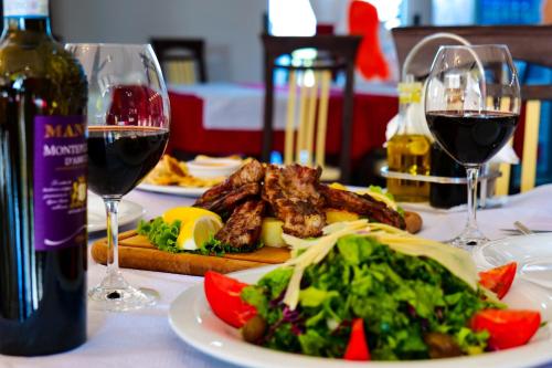 a table with a plate of food and two glasses of wine at LORD Hotel in Tirana