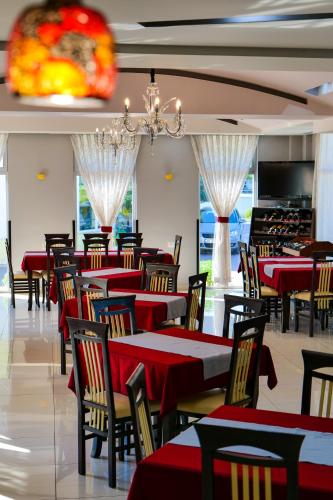 a restaurant with red tables and chairs and a chandelier at LORD Hotel in Tirana