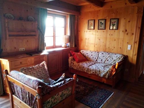ein Wohnzimmer mit einem Sofa und einem Stuhl in der Unterkunft Un bel panorama in un ambiente famigliare in Tesero