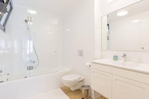 een witte badkamer met een bad, een toilet en een wastafel bij Ocean View in Bat Yam