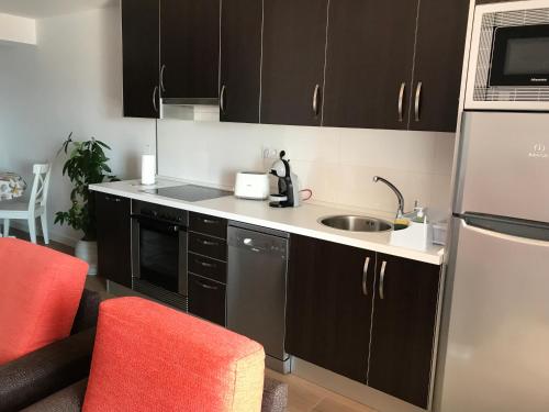 a kitchen with black cabinets and a sink at Apartamento vista al puerto de Finisterre II in Fisterra