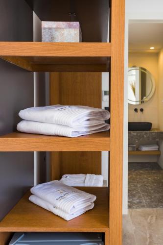 a group of white towels on a wooden shelf at Golden Bay luxury villas and suites in Chrissi Akti