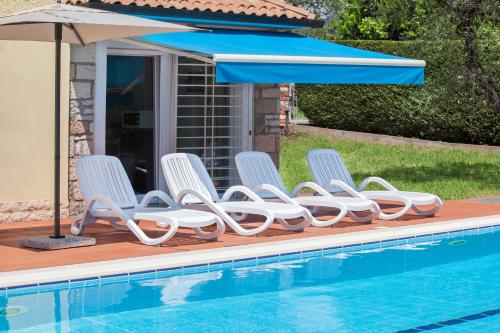 a row of chairs and an umbrella next to a swimming pool at Villa Rose With Pool in Bardolino