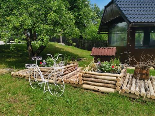 a garden with several logs and flowers in front of a cabin at Green Garden Plitvice lakes in Plitvica selo